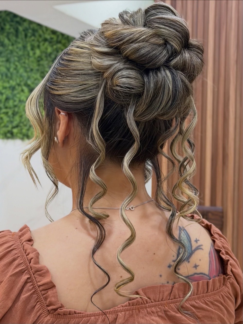 Coque alto com cachos soltos e mechas iluminadas